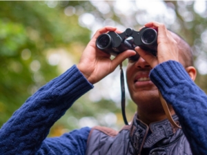 stock photo; black birdwatcher looking through binoculars