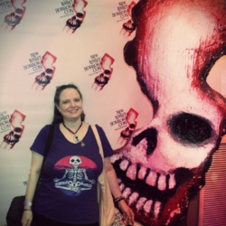 Amber next to the statue prop of the NJ Horror Con logo which is NJ with a a skull shape