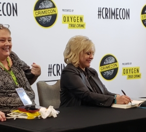 Nancy Grace signing books with assistant at Meet & Greet table