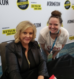 Amber leaning down next to seated Nancy Grace for book signing