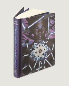 The Binti Trilogy collection shown in hardcover as one book from the Folio Society; book is standing up to show the metallic blue letters of the spine and the art for the front cover.