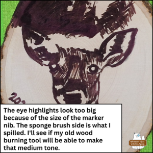 close up of the wooden deer plaque in progress after the heat gun was applied to the Scorch Marker ink; caption: the eye highlights look too big because of the size of the marker nib. The sponge brush side is what I spilled. I'll see if my old wood burning tool will be able to make that medium tone.