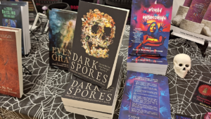 author table featuring a book cover with a skull covered in mushrooms called "Dark Spores" at Books in Bloom