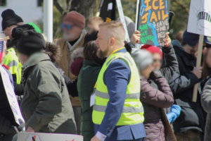 Guy Citron, political activist and candidate, wearing a reflective volunteer vest in front of the crowd.