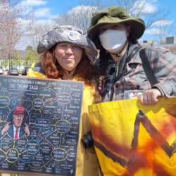 Left: Tracey Heisler holding her protest sign Right: Amber holding her banner Their arms around each others' back.