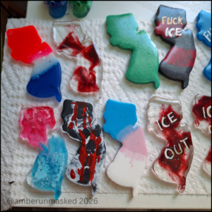 multicolored resin pins in the shape of New Jersey with different patterns; a few on the right with hand-painted text, "Fuck ICE" or "ICE out."